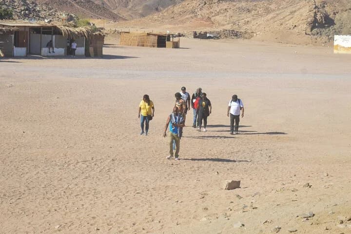 Un groupe de touristes s'approchant de la caméra à pied à travers le camp du désert de Charm el-Cheikh