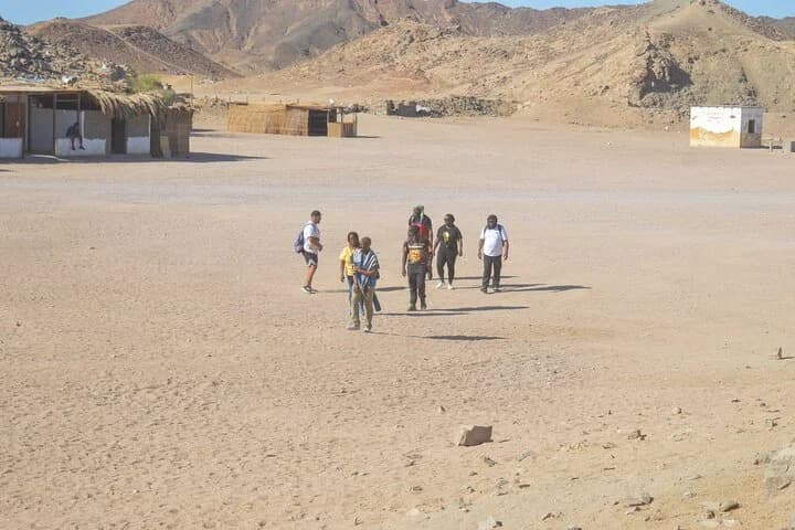 Les participants à la visite traversent la zone sablonneuse du camp bédouin entourée de montagnes arides à Charm el-Cheikh