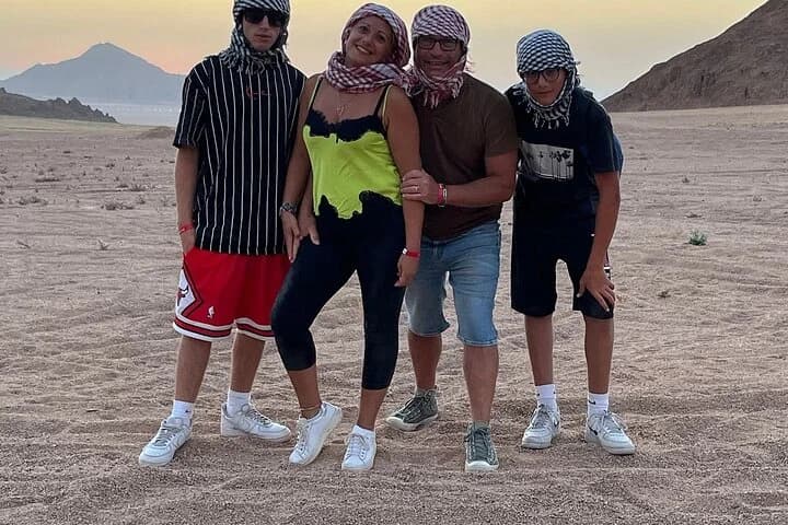 Quatre touristes posant ensemble dans une vallée désertique rocheuse avec des sommets derrière eux pendant le safari de Charm el-Cheikh