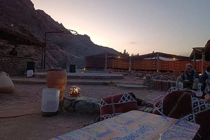 Le camp du désert qui brille au crépuscule avec des sièges illuminés, des tapis, des coussins et une petite lanterne au premier plan à Charm el-Cheikh