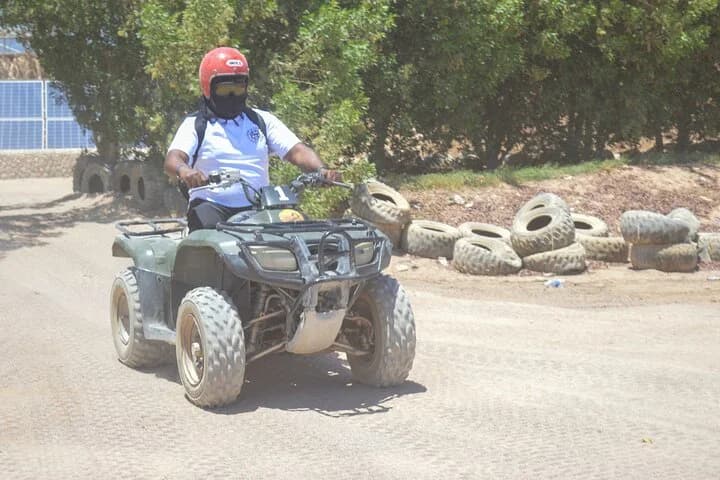 Un motard conduisant un quad VTT à côté de marques de pneus sur un parcours de safari dans le désert de Charm el-Cheikh