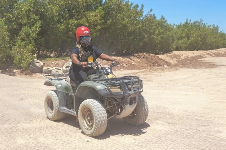 Un visiteur casqué conduisant un quad VTT sur une piste de safari sablonneuse dans le désert de Charm el-Cheikh