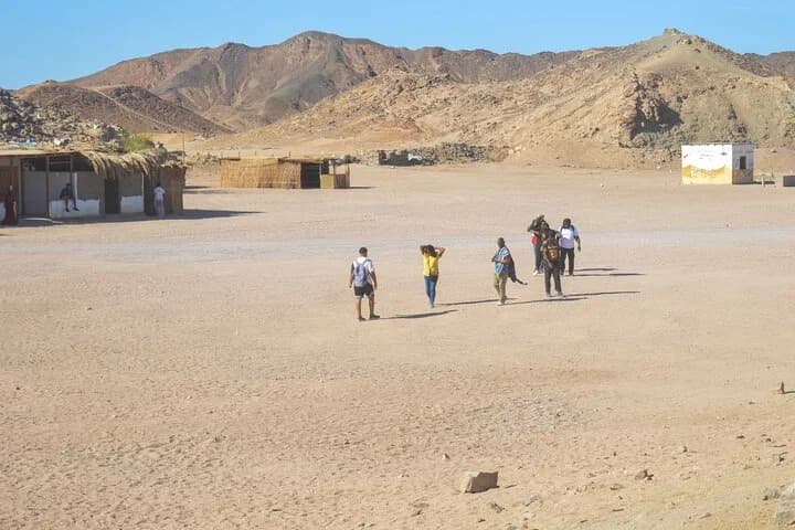 Un petit groupe de visiteurs traverse le camp du désert en direction de cabanes bédouines traditionnelles à Charm el-Cheikh