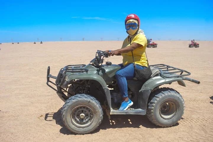 Un touriste assis sur un quad VTT dans le désert ouvert de Charm el-Cheikh, avec d'autres quads au loin
