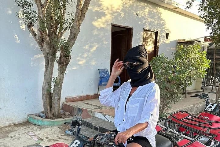 Un touriste en tenue de randonnée dans le désert assis sur un VTT à l'extérieur d'un campement à Charm el-Cheikh, portant un masque facial contre la poussière