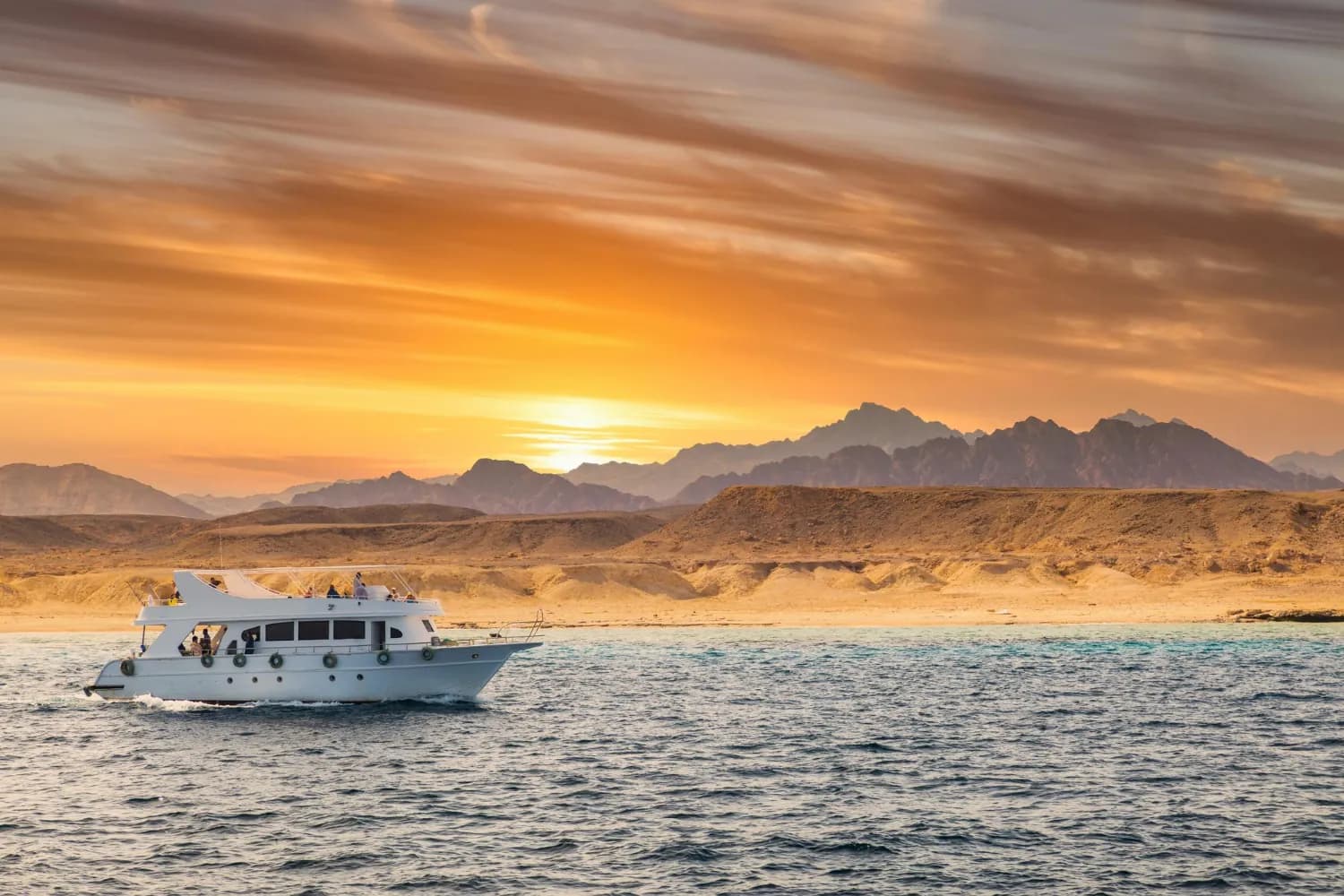 Tour boat sailing past the Sinai mountains at sunset on a Sharm El Sheikh boat trip