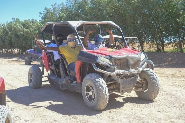 Touristes à bord d'un buggy tout-terrain rouge à travers le désert de Charm el-Cheikh, saluant la caméra